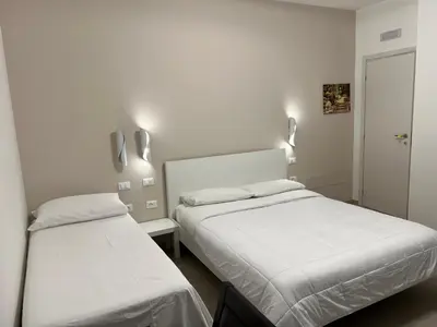 two beds in a room with white walls at CESARE ROOMS in Palermo