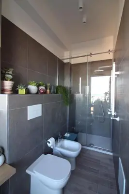 a bathroom with a toilet and a glass shower at Seaview Apartments in Palermo