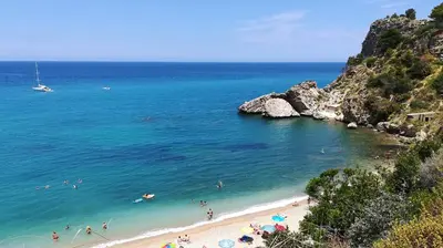 a beach with a bunch of people swimming in the water at Villa Caterina Scopello in Scopello