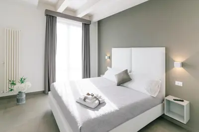 a white bedroom with a large bed with white sheets and pillows at Boutique BnB Dolcevita in Palermo