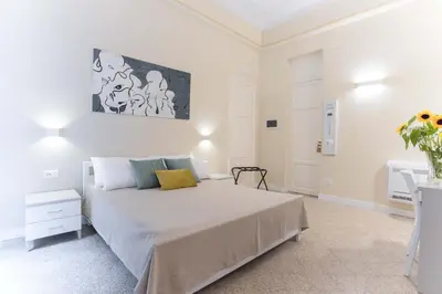 a white bedroom with a bed and a painting on the wall at Donna Isa B&B in Palermo