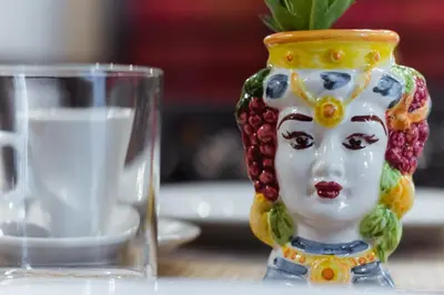 a statue of a woman with grapes on her head next to a glass at Donna Isa B&B in Palermo