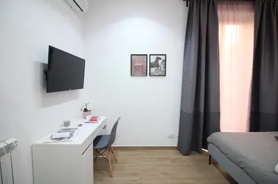 a room with a desk with a computer and a bed at Solli Rooms in Palermo