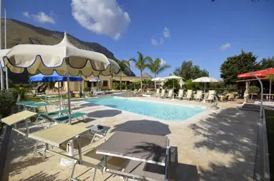 a pool with chairs and umbrellas next to a resort at Hotel Oasi da Paolo in Castelluzzo