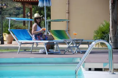 a woman sitting in a chair next to a pool at Hotel Oasi da Paolo in Castelluzzo