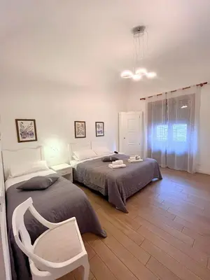 a bedroom with two beds and a chair in it at Giulio Cesare 14, Residence in Palermo