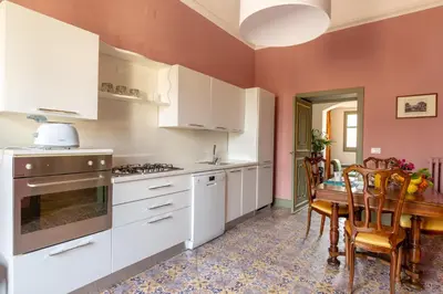 a kitchen with white cabinets and a table and a dining room at Ajutamicristo Domus by DomuSicily in Palermo