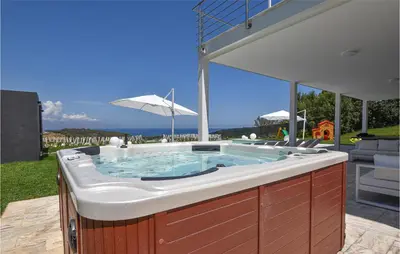 a jacuzzi tub in a backyard with an umbrella at Stunning Home In Balestrate in Balestrate