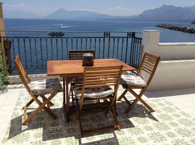 a wooden table and chairs with a view of the ocean at Casa nel borgo marinaro di Santa Nicolicchia in Santa Flavia