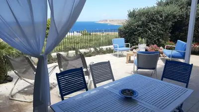 a blue table and chairs on a patio with the ocean at stella di ponente in Macari