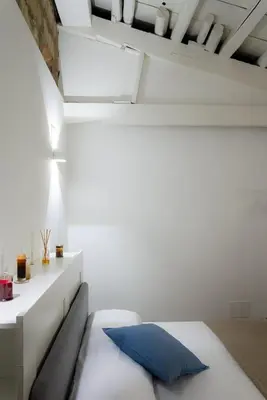 a white bed with a blue pillow in a room at Piazza Florio Rooms in Palermo