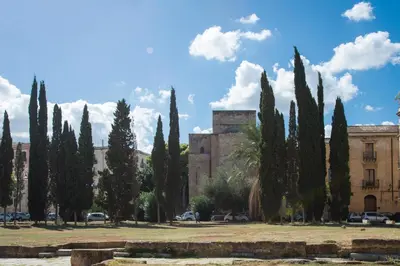 a row of cyprus trees in front of a building at Magione Apartment with Terrace by Wonderful Italy in Palermo