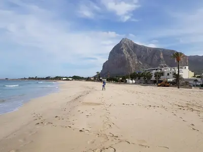 a person standing on a beach with a mountain in the background at Villa Mendez in Castellammare del Golfo