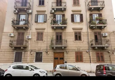 two cars parked in front of a building with windows at Charmie flat in Palermo
