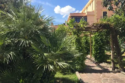 a garden with palm trees and a building at Villa la Rina in Palermo