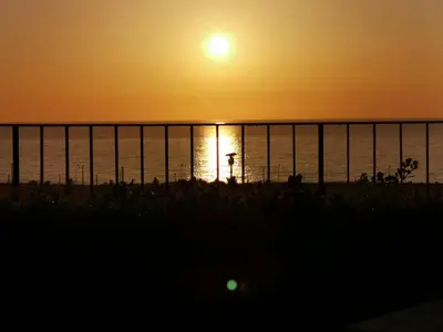 a sunset over the ocean next to a fence at casa Cuffa in San Vito lo Capo