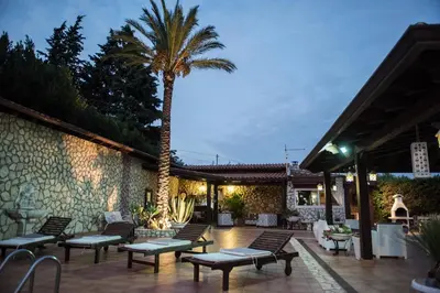 a patio with benches and a palm tree at night at Villa Blondie con piscina a Castellammare del Golfo in Castellammare del Golfo