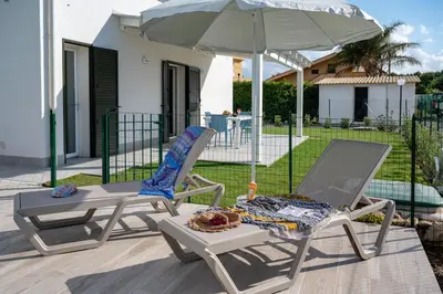 two chairs and an umbrella on a patio at Residence Salinelle Beach Villa Vulcano 4 in Lascari