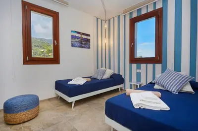 a bedroom with two beds and two windows at Villa della Pigna in Scopello
