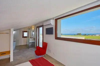 a room with a red chair and a large window at Villa della Pigna in Scopello