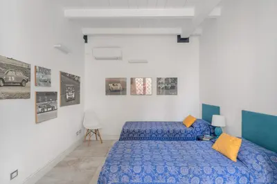 a bedroom with a blue bed in a white room at Valverde Art Space Loft by DomuSicily in Palermo