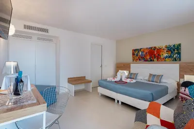 a bedroom with a bed and a table and chairs at Artemide Hotel in San Vito lo Capo