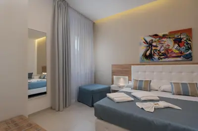 a bedroom with a blue bed and a mirror at Artemide Hotel in San Vito lo Capo