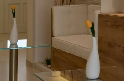 two white vases on a glass table next to a chair at Artemide Hotel in San Vito lo Capo