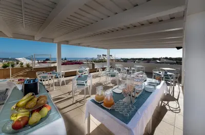 a table with food and drinks on a balcony at Artemide Hotel in San Vito lo Capo