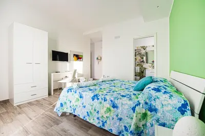 a white bedroom with a bed and a desk at L' Arcobaleno B&B in Castelluzzo