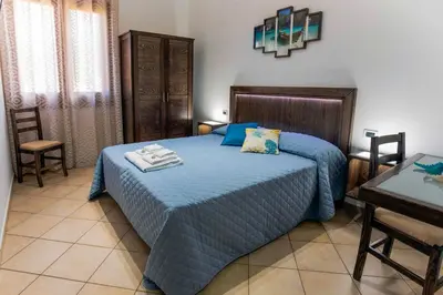 a bedroom with a bed with blue sheets and a table at Perla di Mare Appartamenti in Castelluzzo