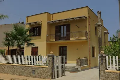 a yellow house with a fence in front of it at Perla di Mare Appartamenti in Castelluzzo