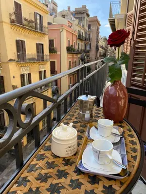 a table with two cups and a vase on a balcony at Casa Vacanze Antico Cassaro in Palermo