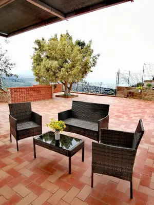a patio with three chairs and a table and a tree at Villa Verde in Cefalù