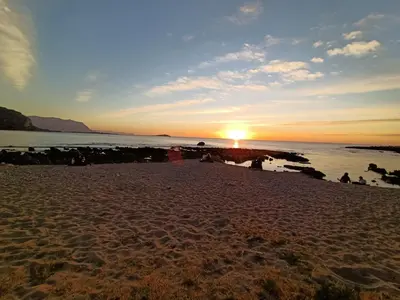 a sunset on a beach with the sun setting at La Casetta di Nonna Anna in Palermo