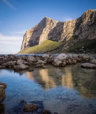 a view of a rocky beach with a mountain in the background at La Casetta di Nonna Anna in Palermo