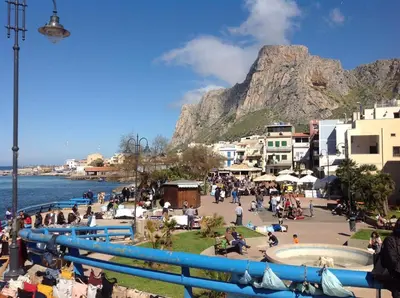 a group of people on a beach with a mountain in the background at La Casetta di Nonna Anna in Palermo