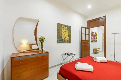 a bedroom with a red bed with a dresser and a mirror at GuestHost - Corso dei Mille Railway Apartment in Palermo