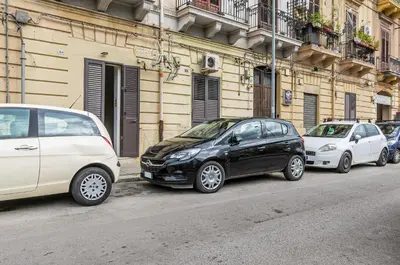 a row of cars parked on the side of a street at GuestHost - Corso dei Mille Railway Apartment in Palermo