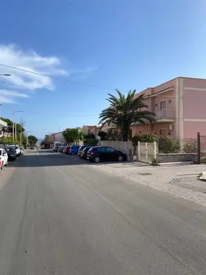 an empty street with cars parked next to a building at Casa Olivella in Santa Flavia