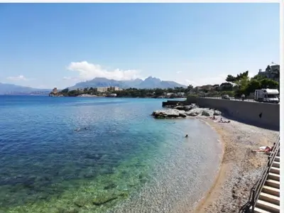 a beach with people swimming in the water at Casa Olivella in Santa Flavia