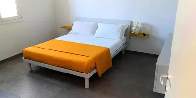 a bed with an orange blanket and white pillows at Villa Cappèddu in Balestrate