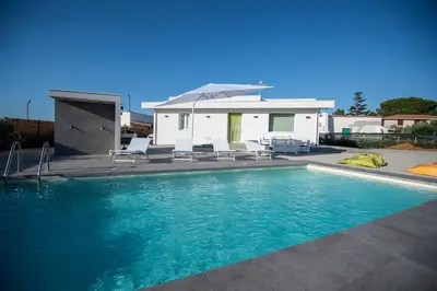 a house with a swimming pool with chairs and an umbrella at Villa Cappèddu in Balestrate