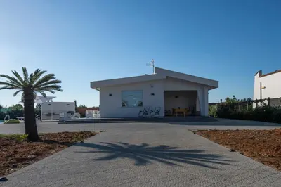 a building with a palm tree in front of it at Villa Cappèddu in Balestrate