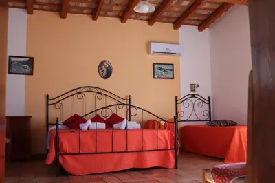 a bedroom with two beds with red sheets at Baglio Cracchiolo Casa Baldo in San Vito lo Capo