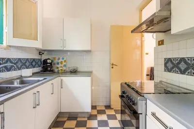 a kitchen with white cabinets and a checkered floor at mondello sea view beach apartment in Palermo