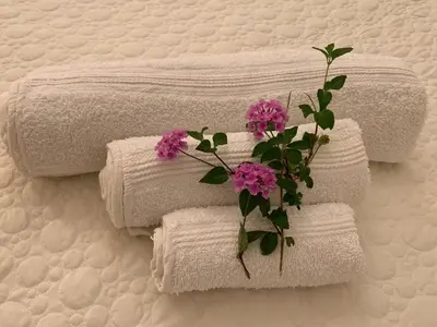 a group of towels with a flower on a bed at mondello sea view beach apartment in Palermo