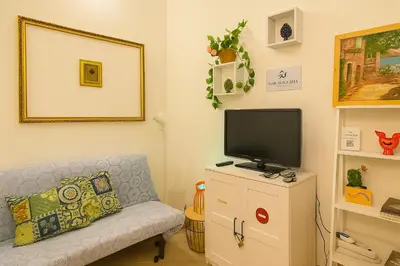 a living room with a couch and a tv on a cabinet at Briogna by Maravigghia Palermo in Palermo