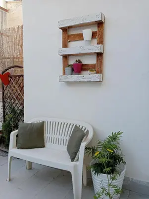 a white bench sitting on a patio with plants at Dietro il massimo in Palermo