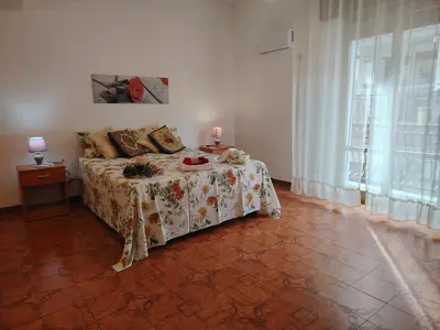 a bedroom with a bed with a floral bedspread and a window at CASA Alle Spezie 1PS Climatizzata in Castellammare del Golfo